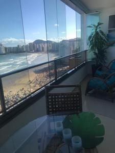 Cette chambre dispose d'une table en verre et offre une vue sur la plage. dans l'établissement Guaruja Praia de Pitangueiras frente ao mar, à Guarujá