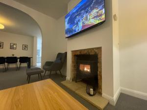 a living room with a fireplace and a tv on the wall at Impressive 4 Bed House Sleeps 8 Private Parking, Fast WiFi 2x Smart TVs Netflix & Foosball, Business Travellers Relocaters Leisure Welcome in Haversham