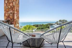 a balcony with chairs and a table and the ocean at Far Horizons Camps Bay in Cape Town