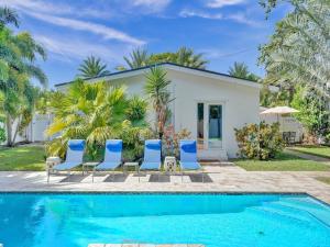 une maison avec une piscine et des chaises bleues dans l'établissement Lush and quiet oasis for 7, pool, close to beach, à Fort Lauderdale