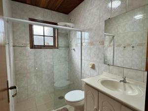 a bathroom with a sink and a toilet and a shower at Casa dos Avós in Campos do Jordão