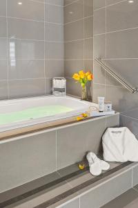 un bagno con vasca e vaso di fiori di Armon Hotel & Conference Center Stamford CT a Stamford