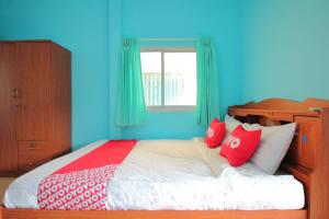 a blue bedroom with a bed with red and white pillows at OYO 496 Chok Phikul Thong Resort in Nakhon Pathom