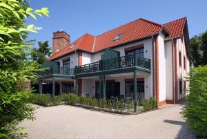 ein Haus mit einem Balkon und einer Ziegelsteinfahrt in der Unterkunft "Windrose" in der Villa am Marienhof in Borkum
