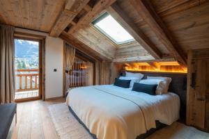 ein Schlafzimmer mit einem großen Bett und einem großen Fenster in der Unterkunft Chalet Enigma in La Clusaz