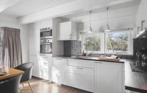 una cucina bianca con elettrodomestici bianchi e tavolo di Four-Bedroom Holiday Home With A Fireplace In Rømø a Toftum