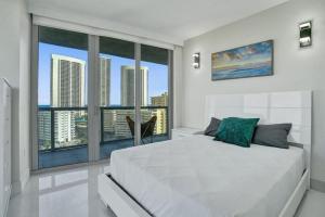 a bedroom with a large white bed and large windows at Gorgeous 4 Bedroom Condo Pool and Stunning Views in Hallandale Beach