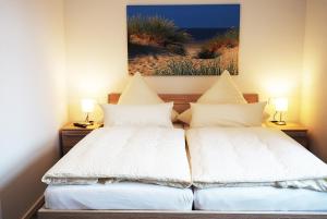 two beds in a room with a picture on the wall at "Kutje" in der Residenz zum Südstrand in Borkum