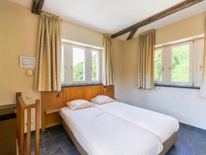 a bedroom with a large bed with two windows at Domaine Château de Dieupart in Aywaille