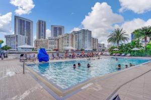 a large swimming pool with people in a city at Stunning Beach Resort Large 4 Bedrooms Apartment in Hallandale Beach