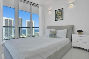 a bedroom with a white bed with a large window at Stunning Beach Resort Large 4 Bedrooms Apartment in Hallandale Beach