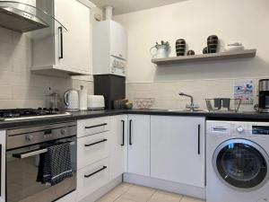 a kitchen with white cabinets and a washing machine at Lovely Serviced Apartment, Free Parking, Oxford in Oxford