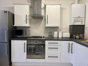 a kitchen with white cabinets and a stove top oven at Lovely Serviced Apartment, Free Parking, Oxford in Oxford