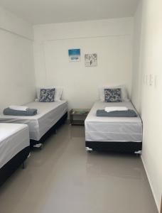 two beds in a room with white walls at Ap em barra grande c/ piscina in Marau +20 photos