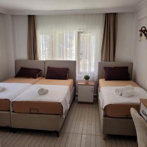1 dormitorio con 2 camas y ventana en OTELIA PANSIYON, en Ayvalık