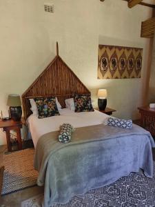 a bedroom with a large bed with a large wooden headboard at Dar Amane Guest House in Graskop
