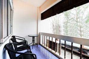 a balcony with two chairs and a table and a window at OYO 629 Chaytalay Palace Hotel in Nathon