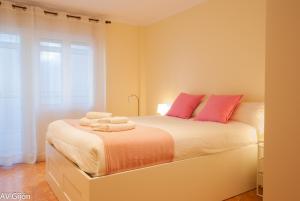 1 dormitorio con 1 cama blanca grande con almohadas rosas en AV Gijón Manso 20, en Gijón