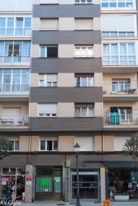 un edificio de apartamentos alto con ventanas y luz de la calle en AV Gijón Manso 20, en Gijón