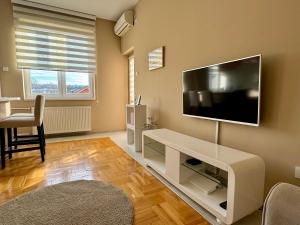 een woonkamer met een flatscreen-tv aan de muur bij Trident Apartments 3 in Niš