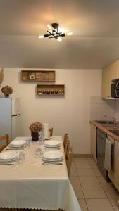 uma cozinha com uma mesa com pratos e copos em Chalet paisible à la plage, piscine et tennis em Ondres