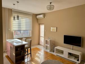 een woonkamer met een flatscreen-tv en een bureau bij Trident Apartments 3 in Niš