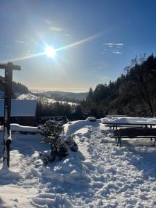 einen schneebedeckten Hof mit einem Picknicktisch und Bänken in der Unterkunft Agropajda in Sokolec