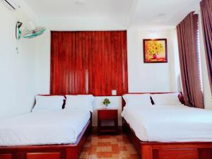 Habitación con 2 camas y cortina roja. en GERBERA HOTEL, en Quy Nhon