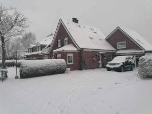 una casa con un coche aparcado en la nieve en Hotel Pension Friesenruh, en Bensersiel