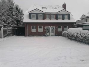 a house with a snow covered driveway in front of it at Hotel Pension Friesenruh in Bensersiel