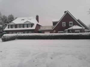ein Haus mit Schnee auf dem Boden davor in der Unterkunft Hotel Pension Friesenruh in Bensersiel