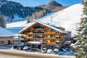 un lodge de esquí con coches aparcados en la nieve en Hotel Alpenrose, en Zauchensee
