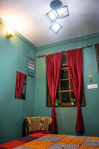 Schlafzimmer mit einem Bett und einem Fenster mit roten Vorhängen in der Unterkunft Family Homestay Darjeeling in Darjeeling