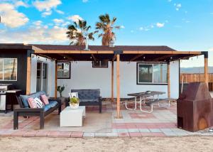un patio con techo, mesa y sillas en Twin Palms Desert Getaway - Jacuzzi, Fire pit, Meditation room & more en Joshua Tree