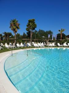 une grande piscine avec des chaises et des palmiers dans l'établissement Resort Acqua di Venere, à Paestum