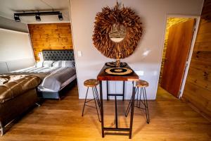 1 dormitorio con cama y mesa con taburetes en OMM Suites Resort, Villa General Belgrano en Villa General Belgrano