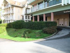 a building with a green hedge next to a street at Résidence Le Cheverny - Studio pour 2 Personnes 194 in Aix-les-Bains