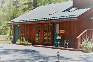 a small red house with a metal roof at River Hideout: One Bedroom Duplex Cottage ON THE RIVER!! in Ruidoso