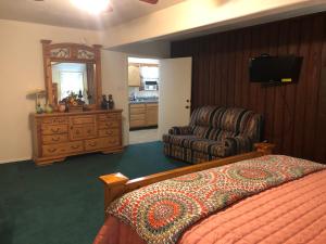 a bedroom with a bed and a chair and a dresser at River Hideout: One Bedroom Duplex Cottage ON THE RIVER!! in Ruidoso