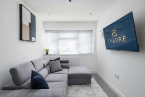 a living room with a gray couch and a window at 4bed perfect for contractors & Long Stays By Valore Property Services in Milton Keynes