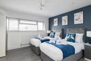 ミルトン・キーンズにある4bed perfect for contractors & Long Stays By Valore Property Servicesの青い壁のベッドルーム1室(ベッド2台付)