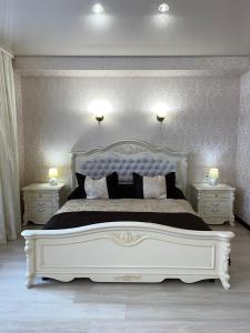 a bedroom with a large white bed with two night stands at Maximus hotel in Lutsk