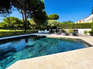 a swimming pool in a yard with chairs and trees at Villa Du Golf De La Grande Motte - Maisons & Villas pour 12 Perso 044 in La Grande Motte