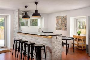 a kitchen with a bar with black stools at Casa da Azenha - Quinta do Boição - Private pool in Bucelas