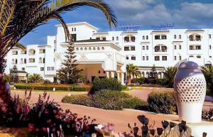 a large white building with a garden in front of it at Monarque El Fatimi Mahdia in Mahdia