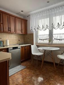a kitchen with wooden cabinets and a table with white chairs at APARTAMENT CENTRUM in Nowe Miasto Lubawskie