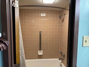 a bathroom with a shower with a tub and a toilet at Super 8 by Wyndham Blytheville in Blytheville