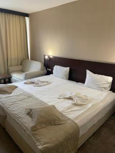 Una cama grande en una habitación de hotel con toallas. en Хотел Ботевград en Botevgrad