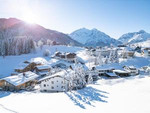 ein schneebedecktes Dorf mit Bergen im Hintergrund in der Unterkunft Lichterberg in Hirschegg