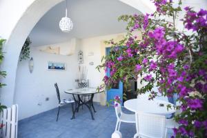 un patio con flores púrpuras, mesa y sillas en Borgo Rio Favara residence - appartamenti, en Santa Maria del Focallo